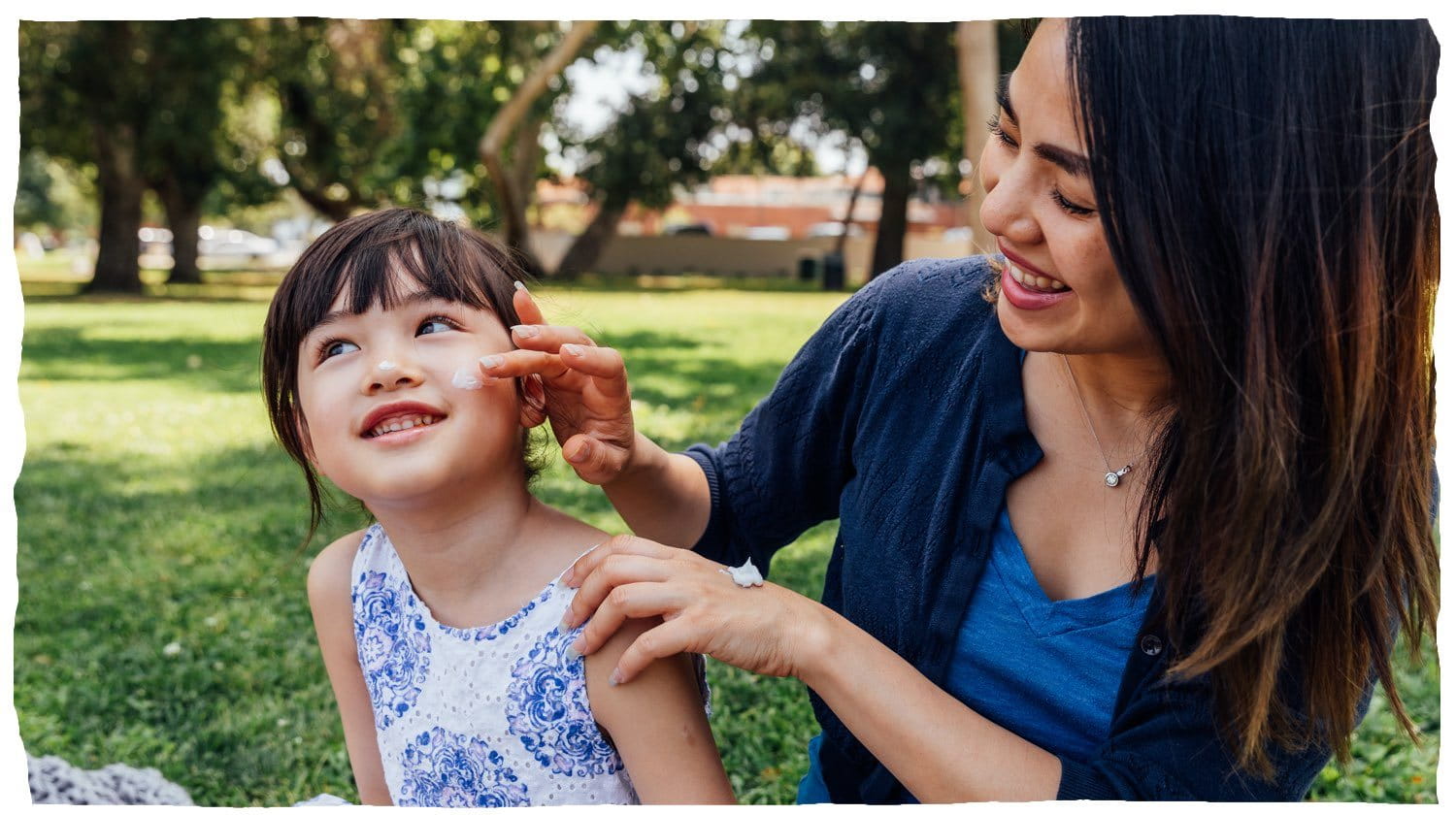 A woman applying lotion to a child’s cheek.